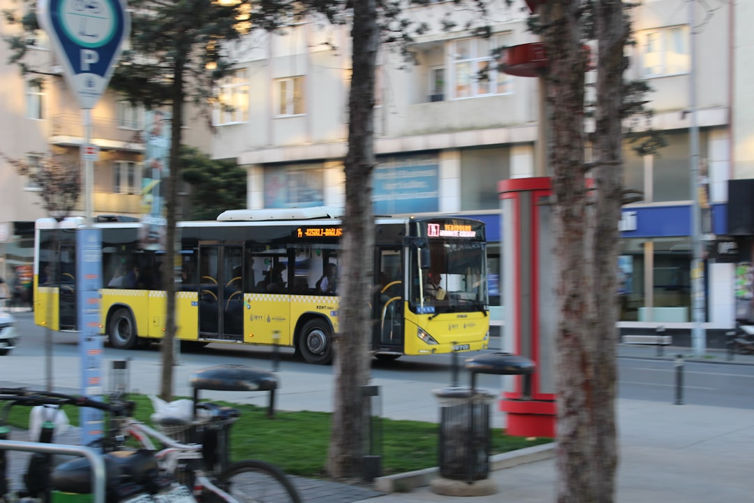 A yellow bus driving down a street next to tall buildings